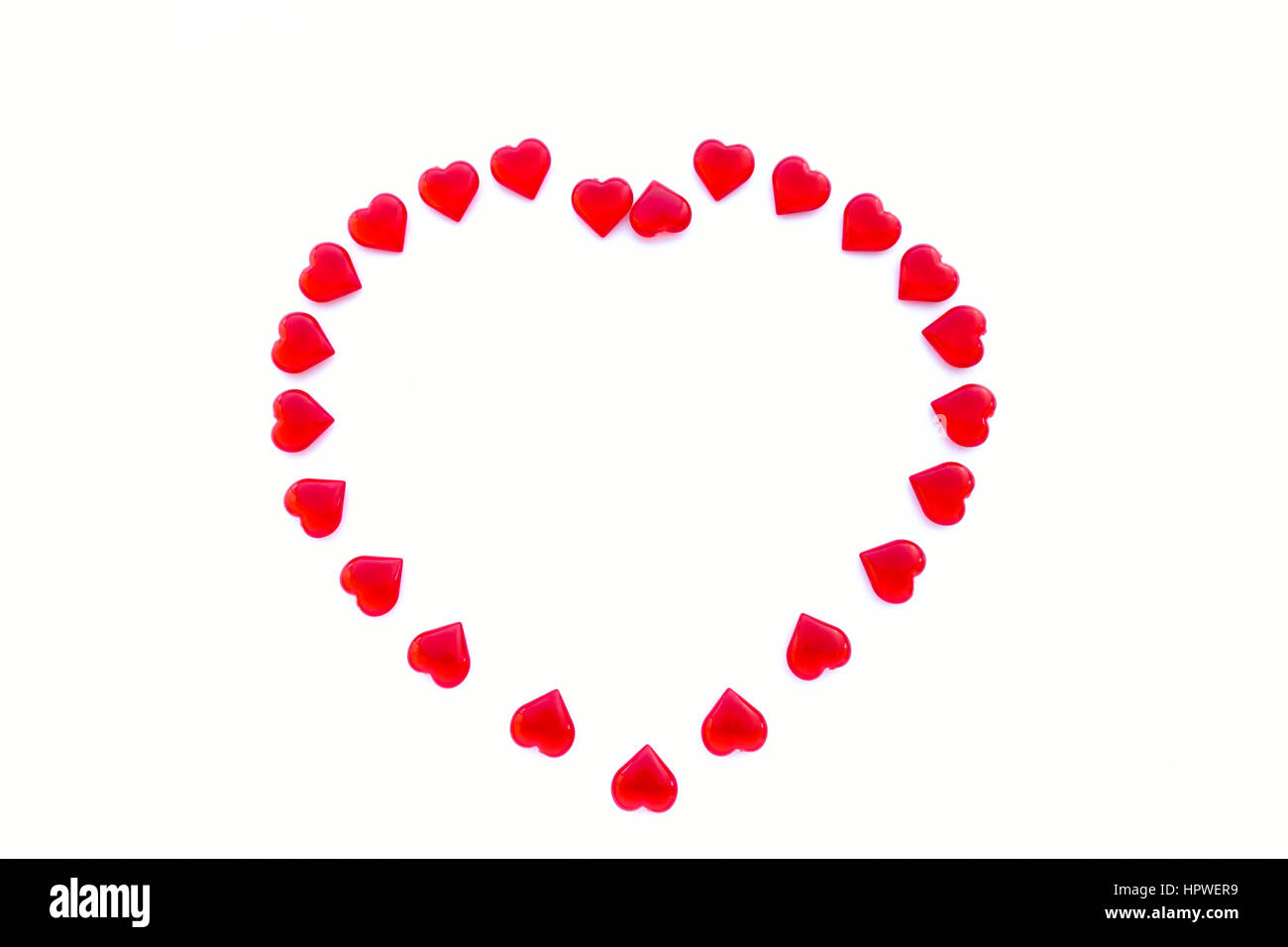 Large heart shaped out of small shiny acrylic red hearts on white background with lots of copy space. Stock Photo
