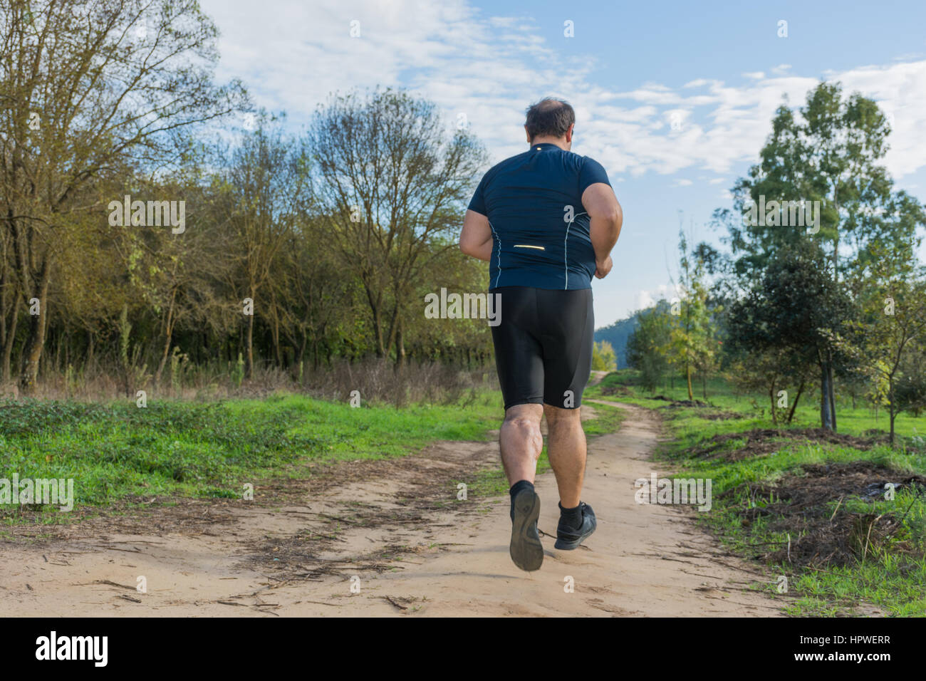 Big belly man jogging , exercising, doing cardio in the park , slightly