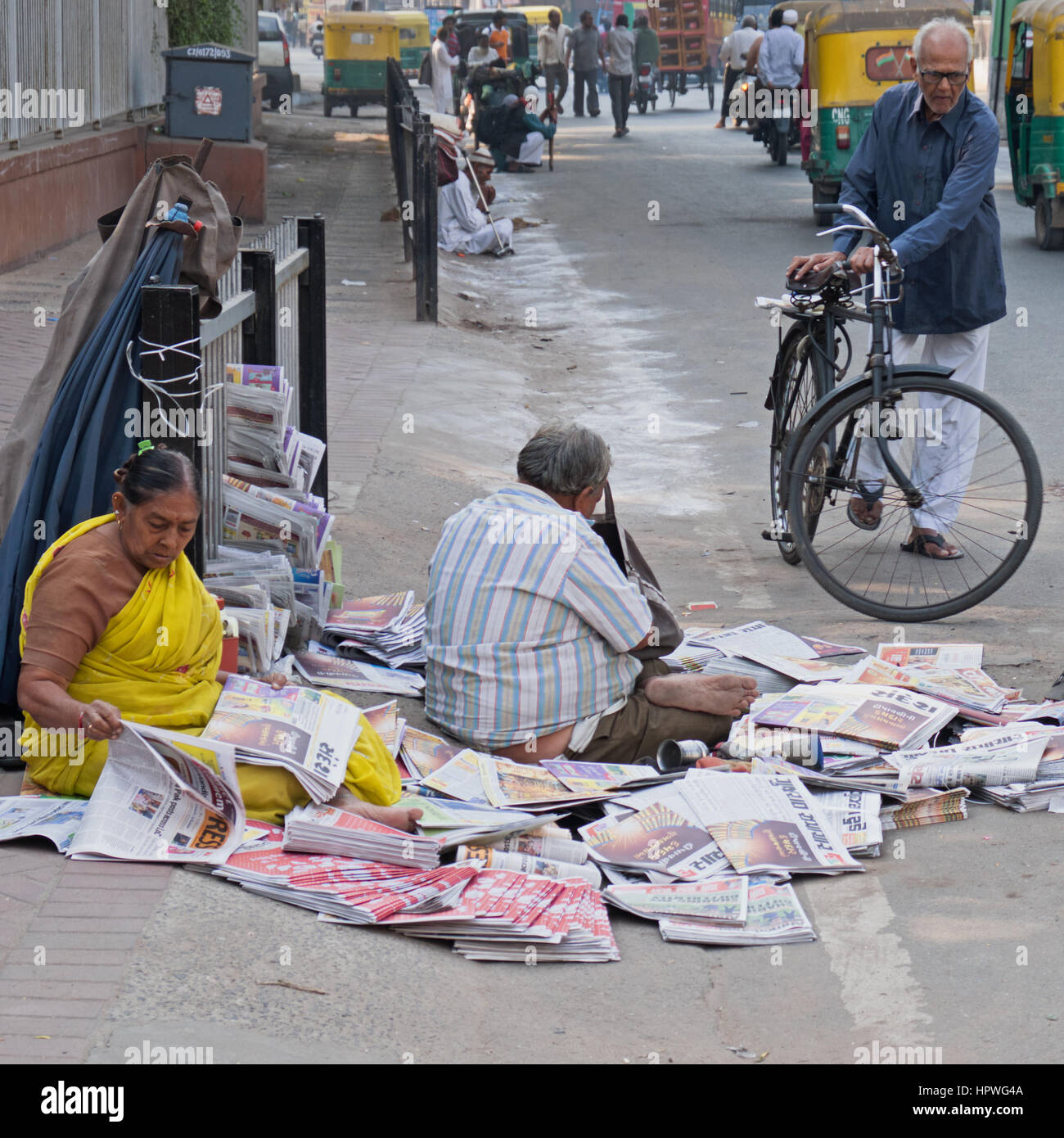 An unidentified newspaper seller with a pitch on a busy street in Ahmedabad, India, amidst the early morning traffic Stock Photo