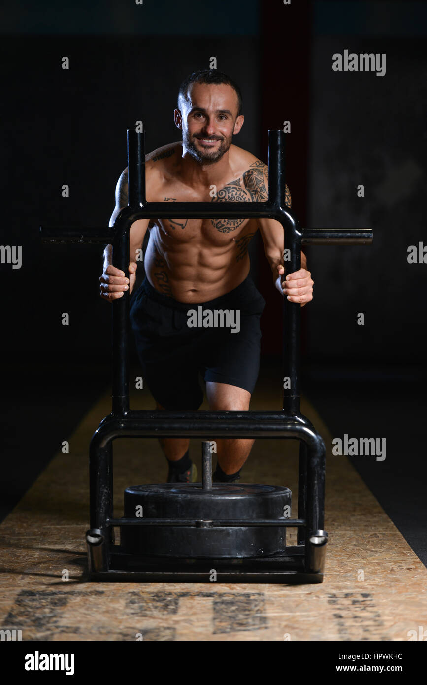 Bodybuilder Doing Heavy Weight Exercise Sled Push In Gym Stock Photo