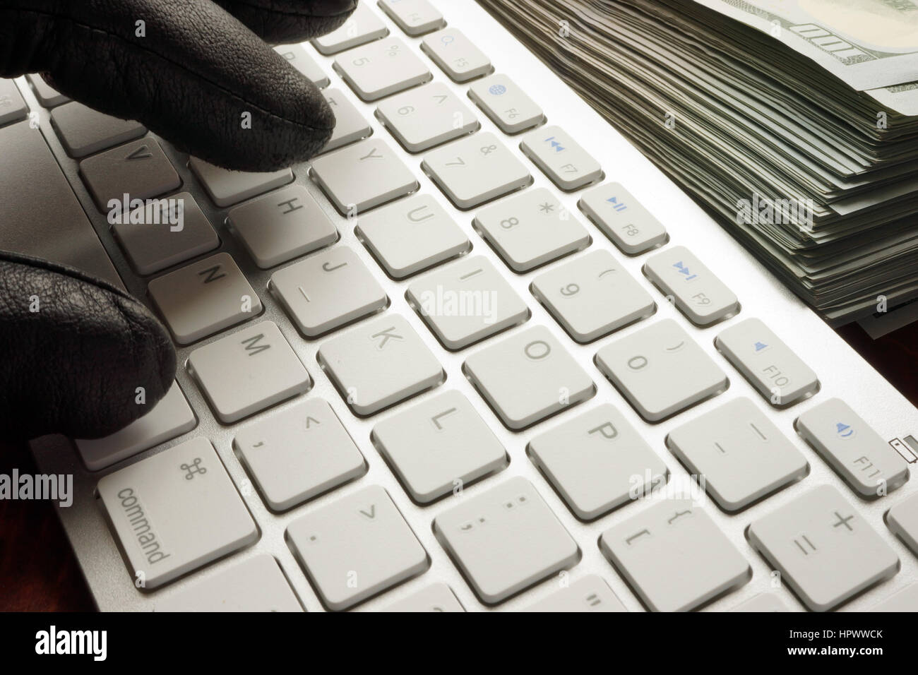 Hand in black glove types on keyboard and dollars. Stock Photo