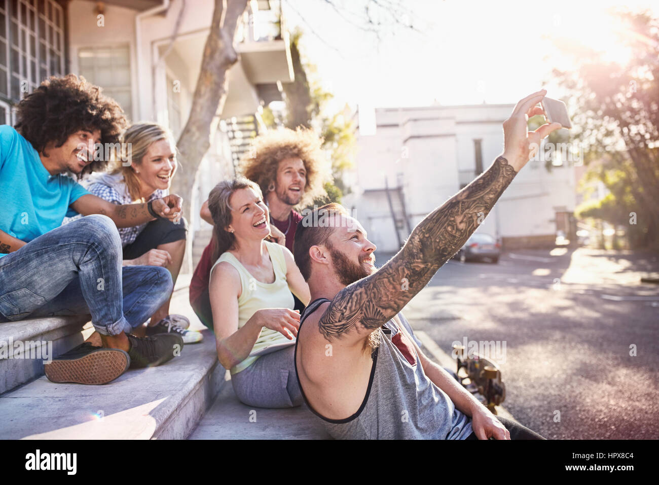 Friends hanging out taking selfie with camera phone on steps Stock Photo