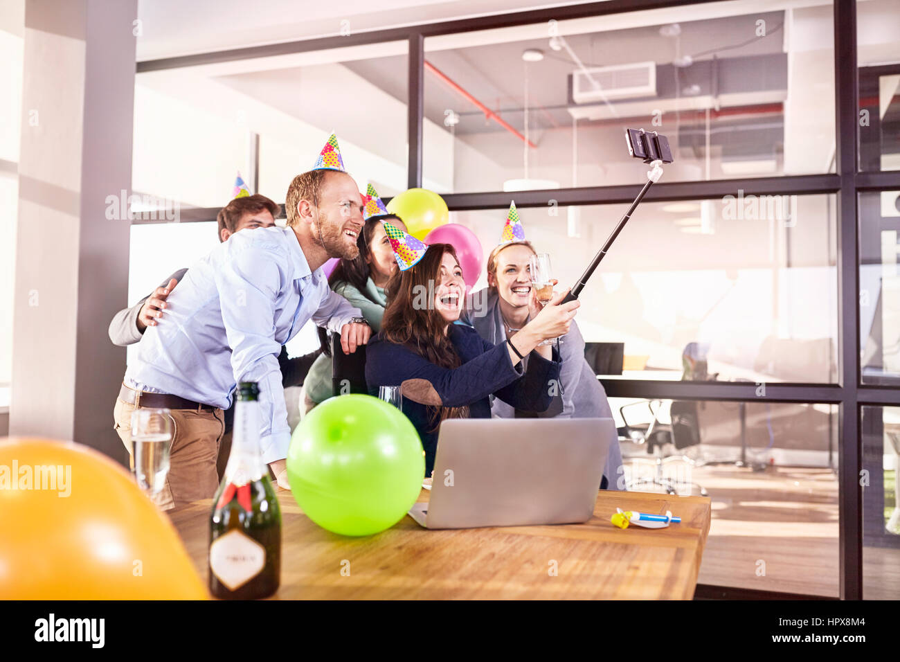 Playful business people celebrating birthday taking selfie with selfie stick in conference room Stock Photo