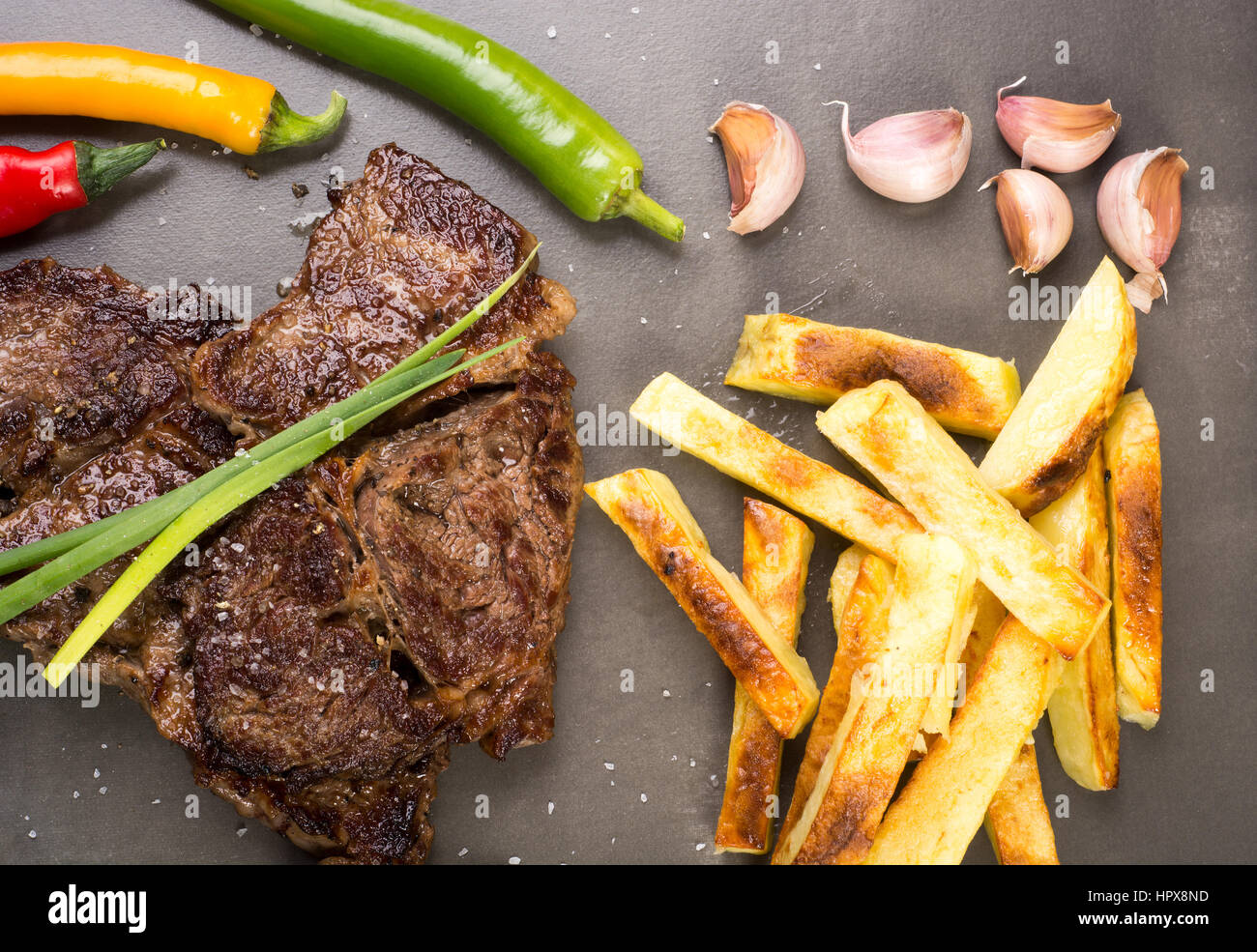 Well done beef steak with chips on dark slate plate Stock Photo