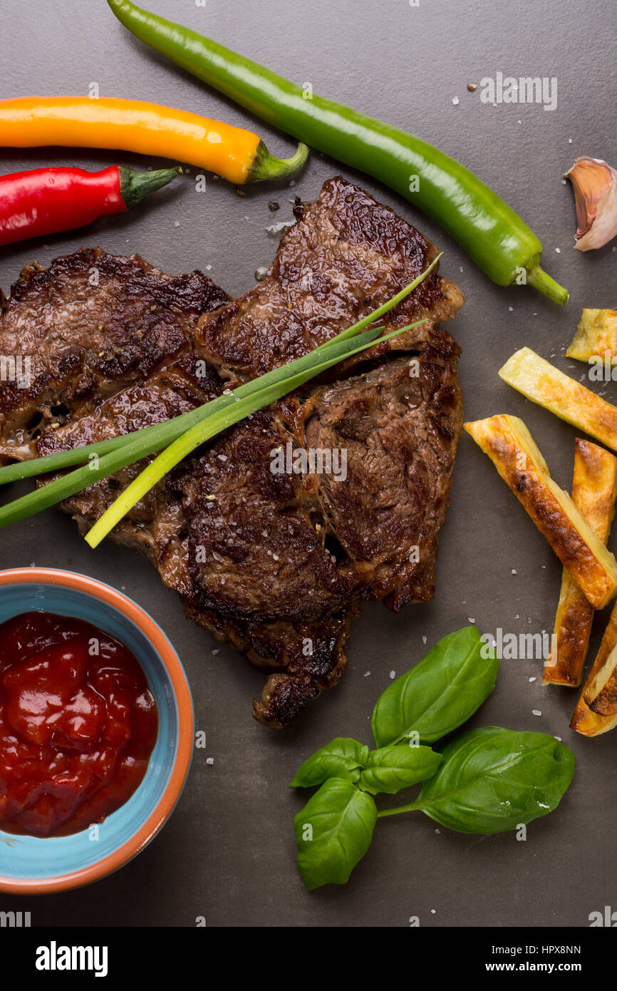 Well done beef steak with chips on dark slate plate Stock Photo
