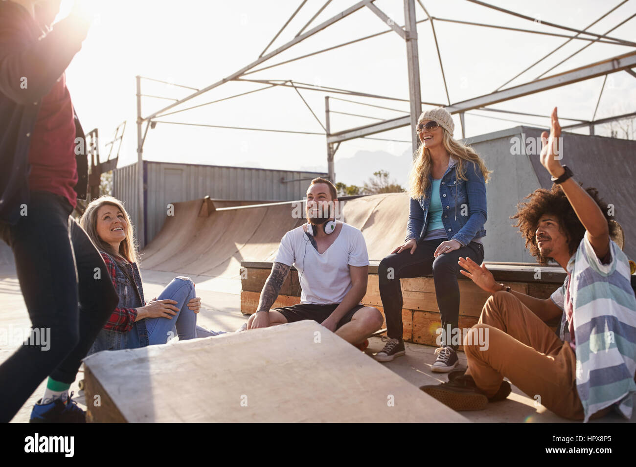 Friends hanging out and dancing at sunny skate park Stock Photo
