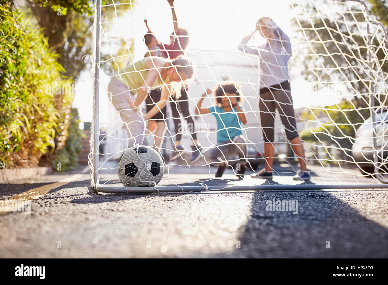 Friends playing soccer on sunny urban summer street Stock Photo