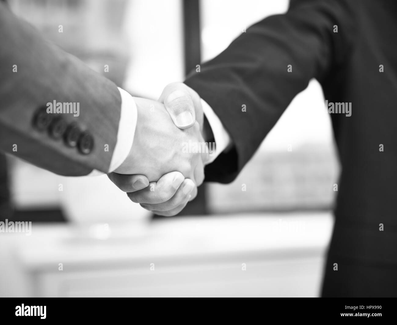 two corporate businessmen shaking hands in office, black and white. Stock Photo