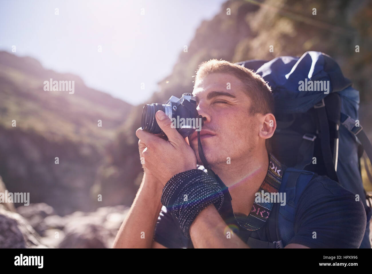 Young man with backpack hiking and photographing with camera Stock Photo
