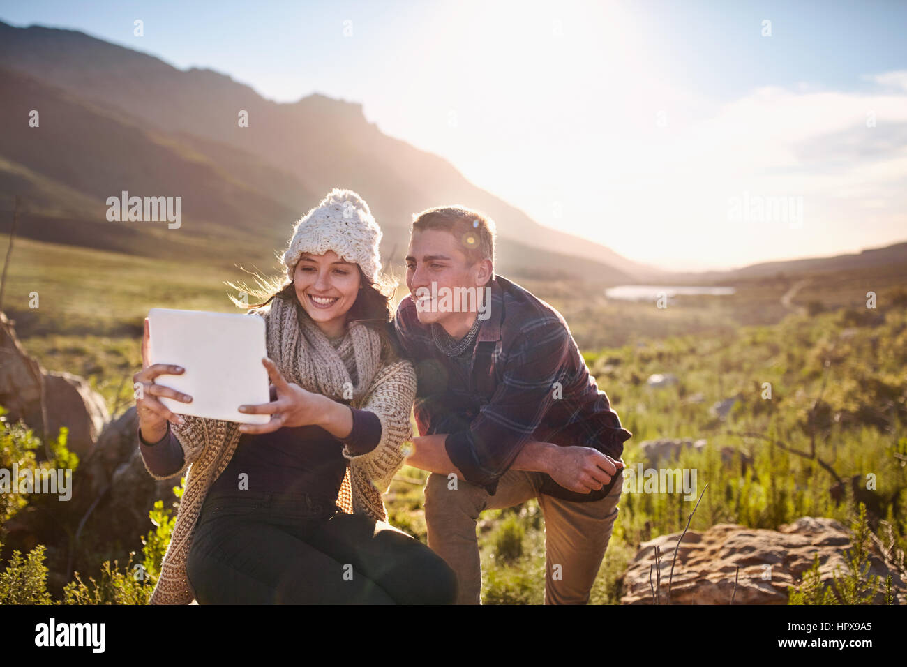 Young couple taking selfie with digital tablet camera in sunny valley Stock Photo
