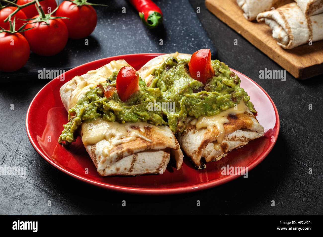 Mexican chimichanga with guacamole dip on a red plate Stock Photo