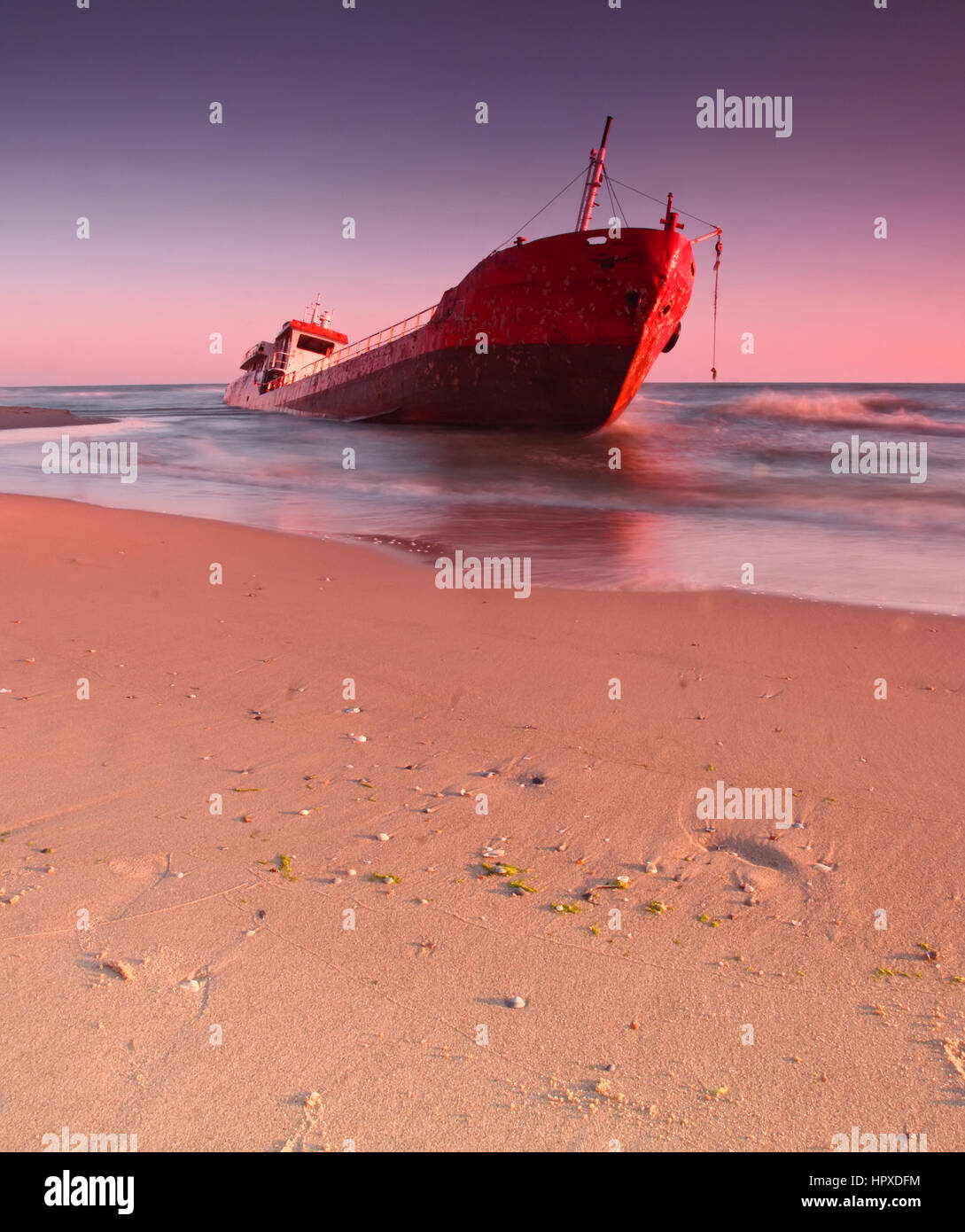 Ship after wreck on the coast with colorful pink sunset Stock Photo