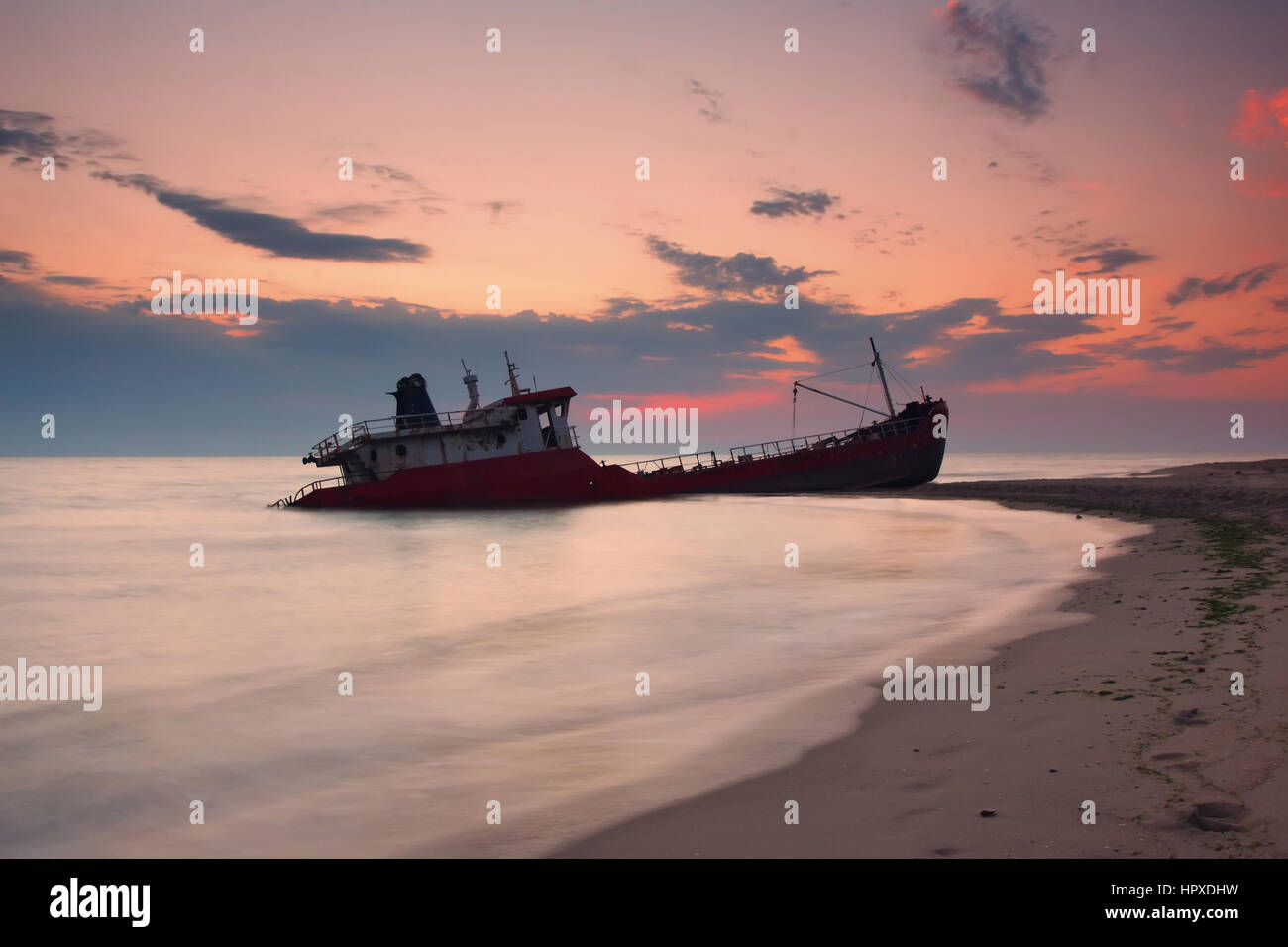 Ship after wreck on the coast during colorful sunset Stock Photo