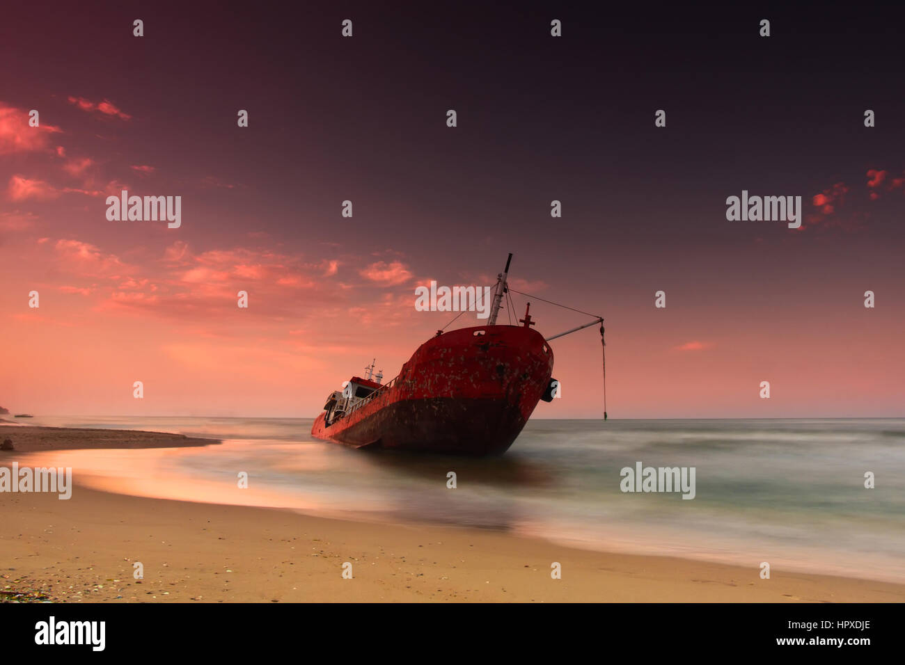 Ship after wreck on the coast with  colorful pink  sunset Stock Photo