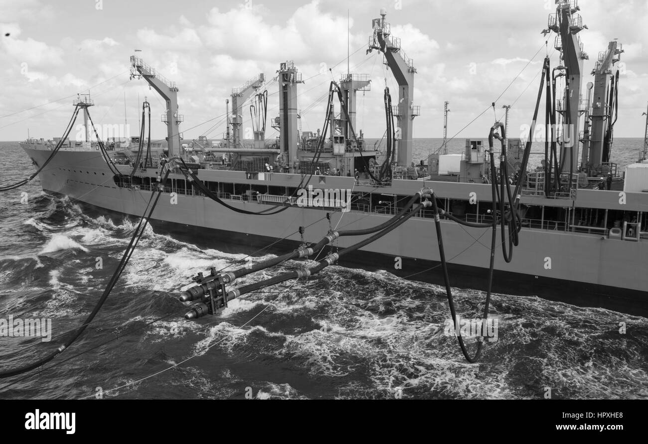 The fleet replenishment oiler USNS Kanawha (T-AO 196) extends fuel lines to the aircraft carrier USS Harry S. Truman (CVN 75) during a replenishment-at-sea, January 26, 2013. Image courtesy US Navy. Stock Photo