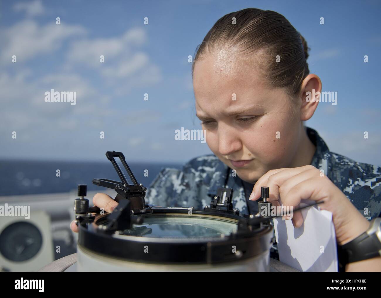 Quartermaster Seaman Kimberly Pups uses an azimuth circle to read the bearing to the sun from the port bridge wing of the Whidbey Island-class amphibious dock landing ship USS Tortuga (LSD 46), February 5, 2013. Image courtesy US Navy. Stock Photo