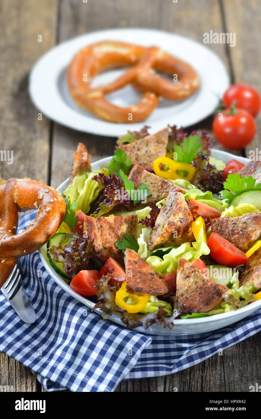 Bavarian salad: Pieces of fried sausage with pig spleen served on a colorful mixed salad Stock Photo
