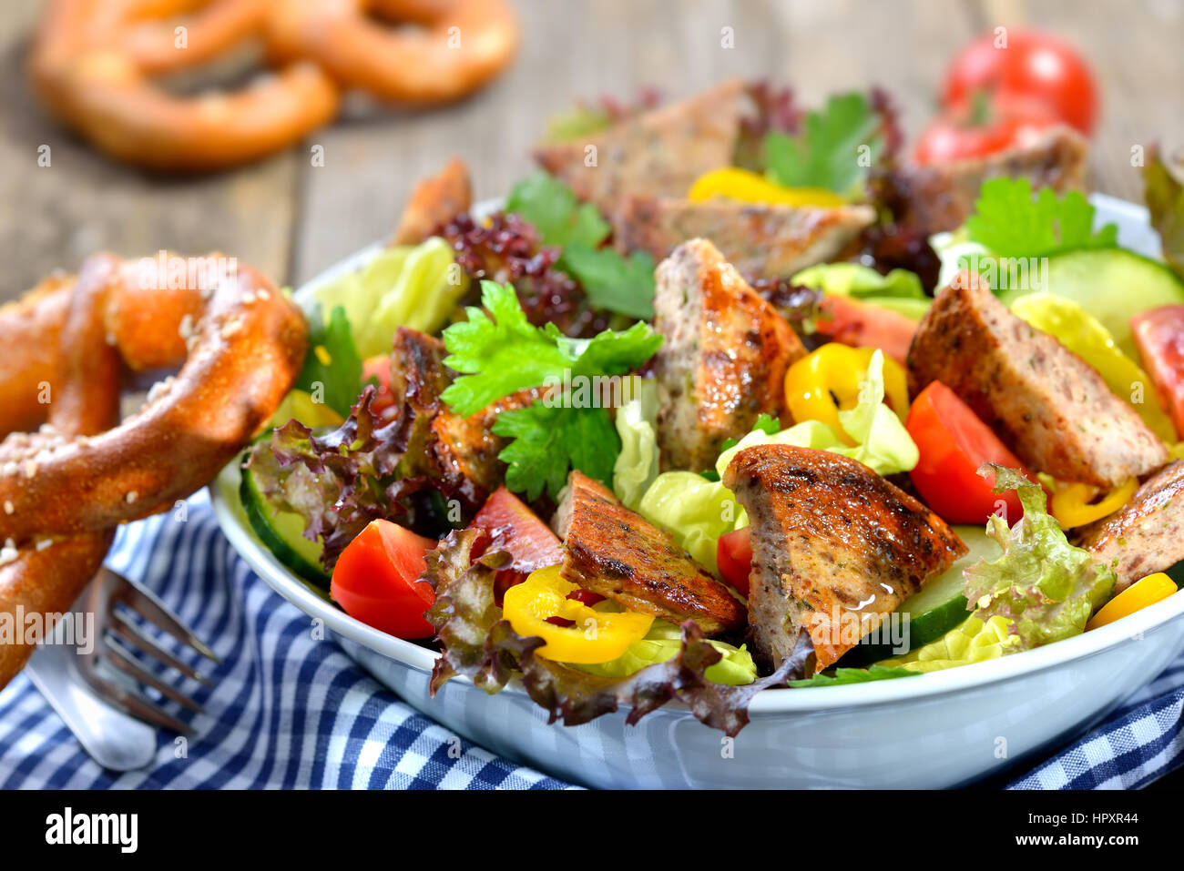 Bavarian salad: Pieces of fried sausage with pig spleen served on a colorful mixed salad Stock Photo