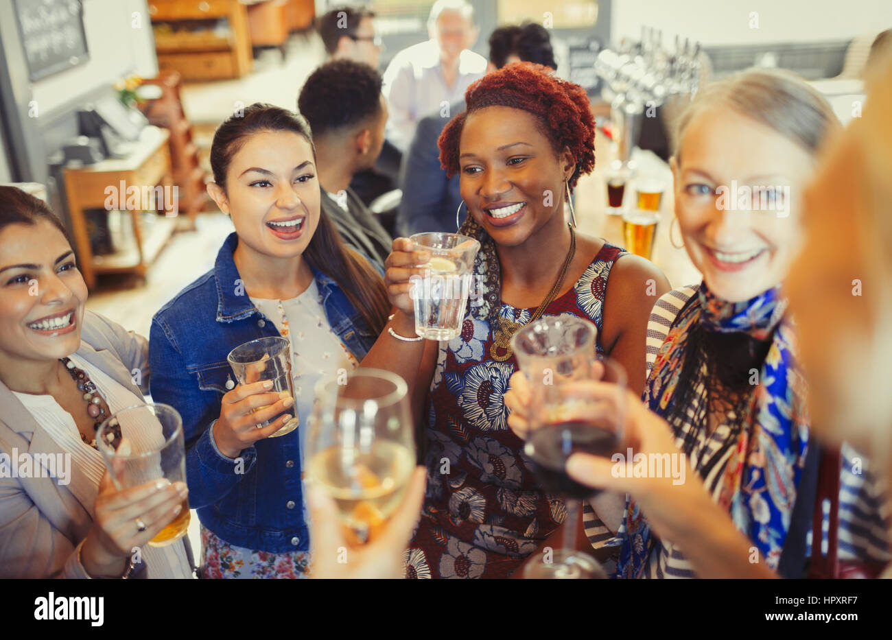 Women friends toasting wine and beer glasses at bar Stock Photo