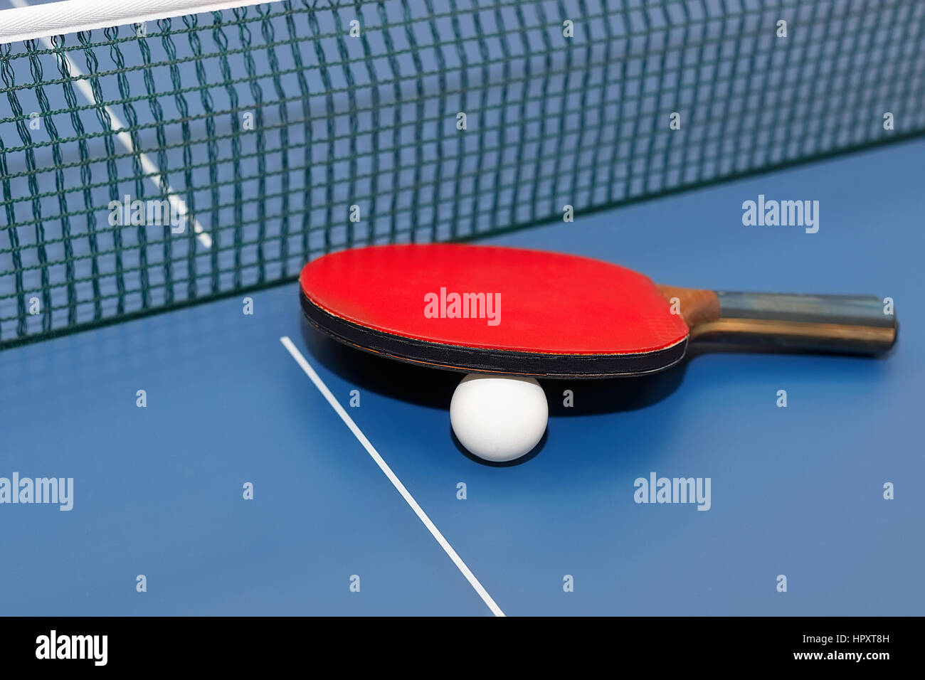 Table tennis racket, white ball and net on a on blue board. Equipment for table tennis. Ping