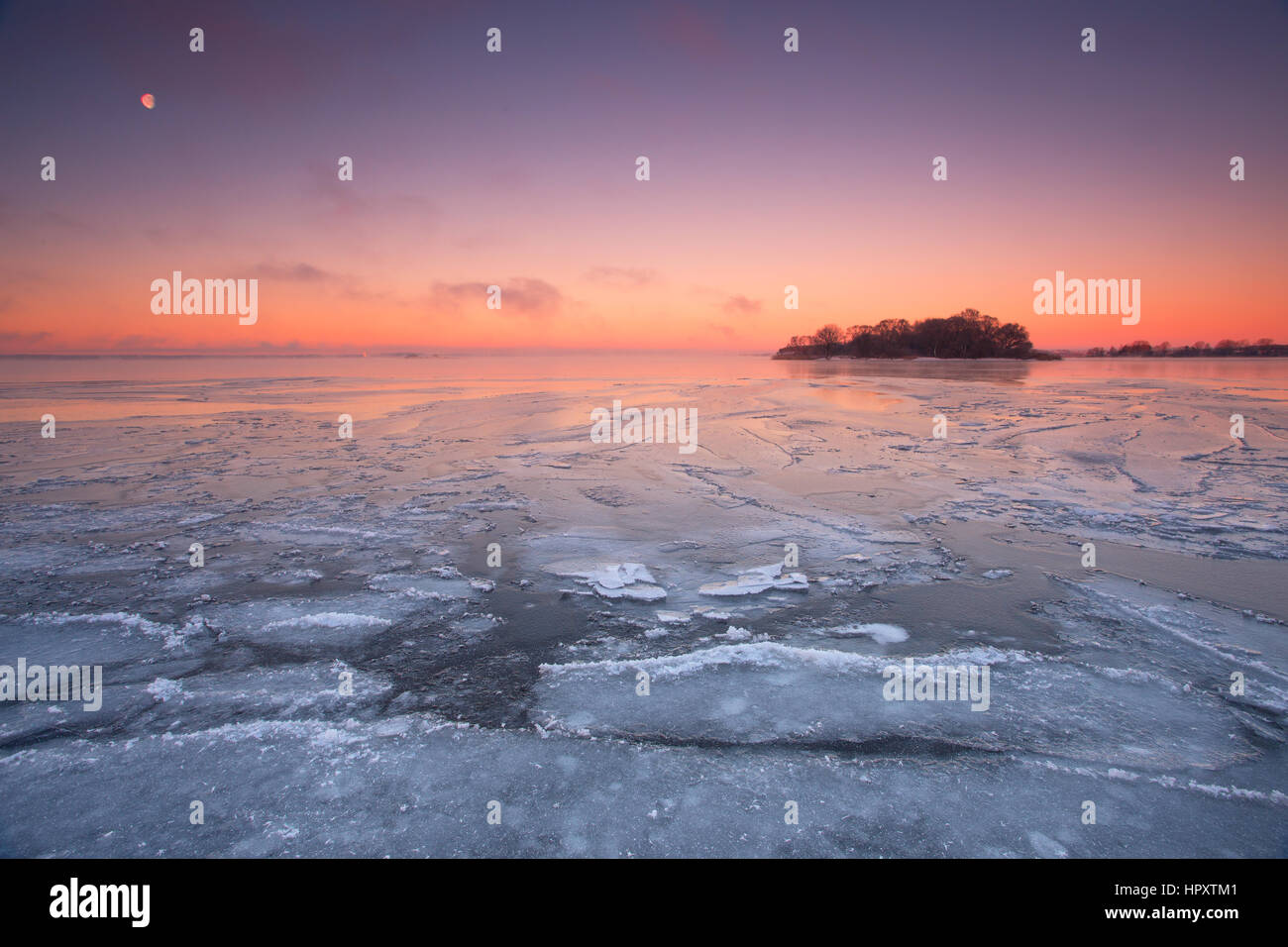 Cold winter morning on the ocean with colorful dawn with the moon Stock Photo