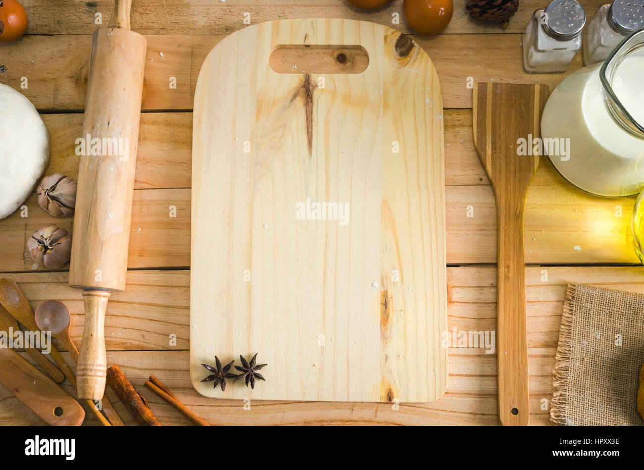 Wooden cutting boards with utensils and bakery ingredients on wooden