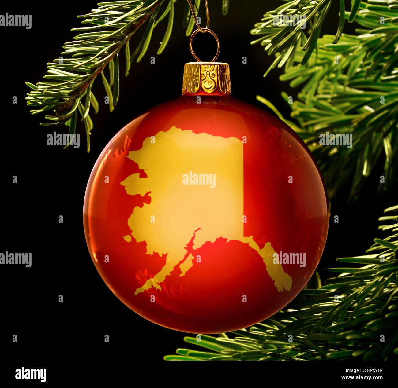 A red bauble with the golden shape of  Alaska hanging on a christmas tree isolated on black.(series) Stock Photo