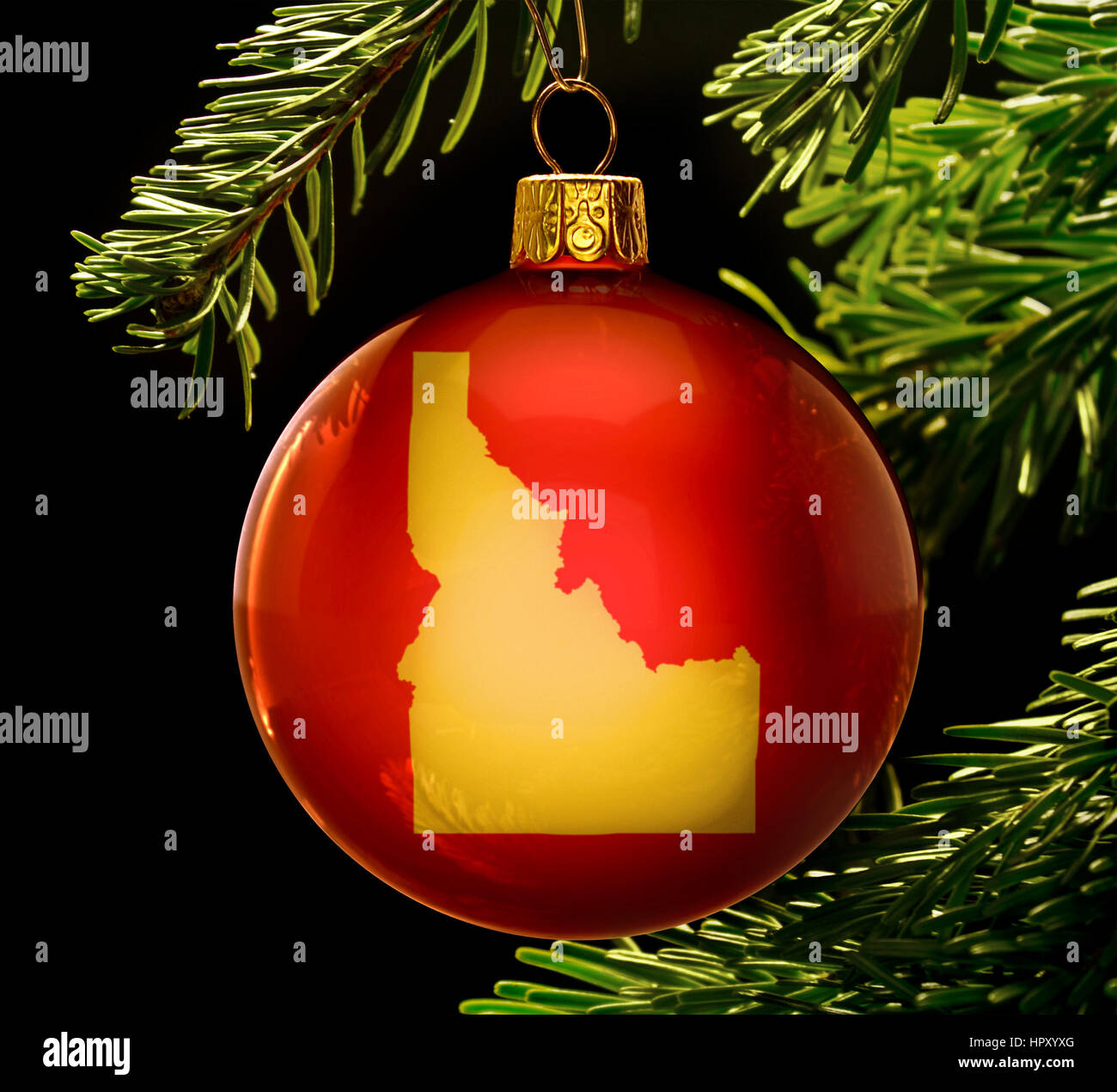 A red bauble with the golden shape of  Idaho hanging on a christmas tree isolated on black.(series) Stock Photo