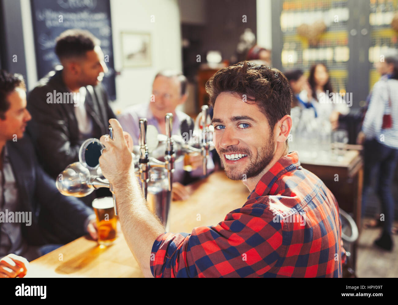 Portrait smiling, confident male bartender serving beer at bar Stock Photo