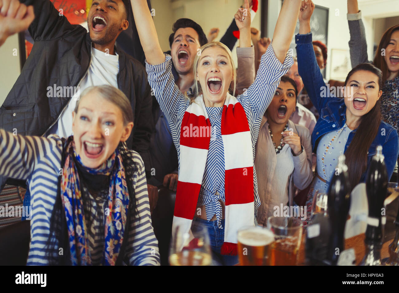Enthusiastic sports fans cheering watching game in bar Stock Photo