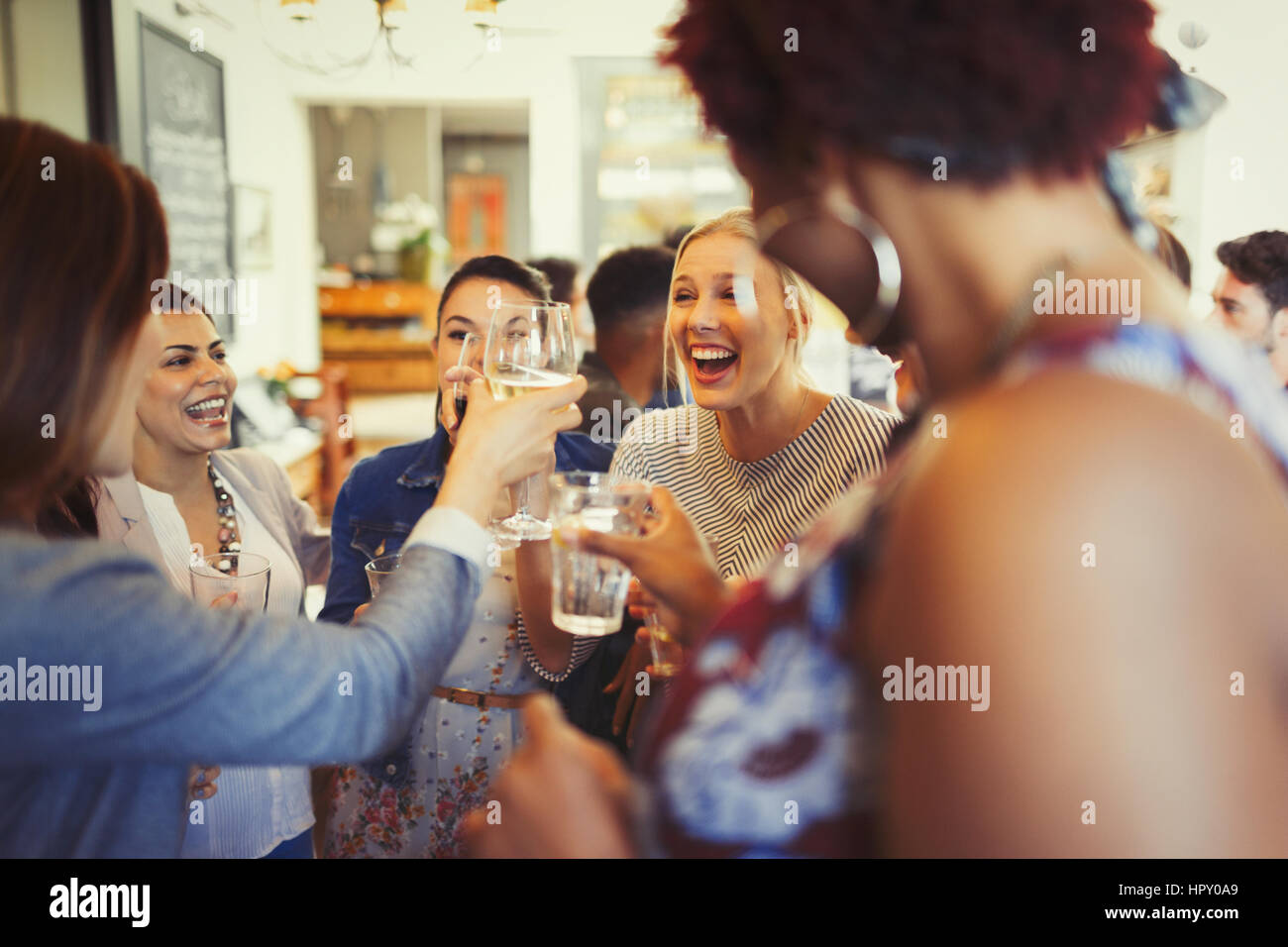 Enthusiastic women friends toasting wine glasses at bar Stock Photo