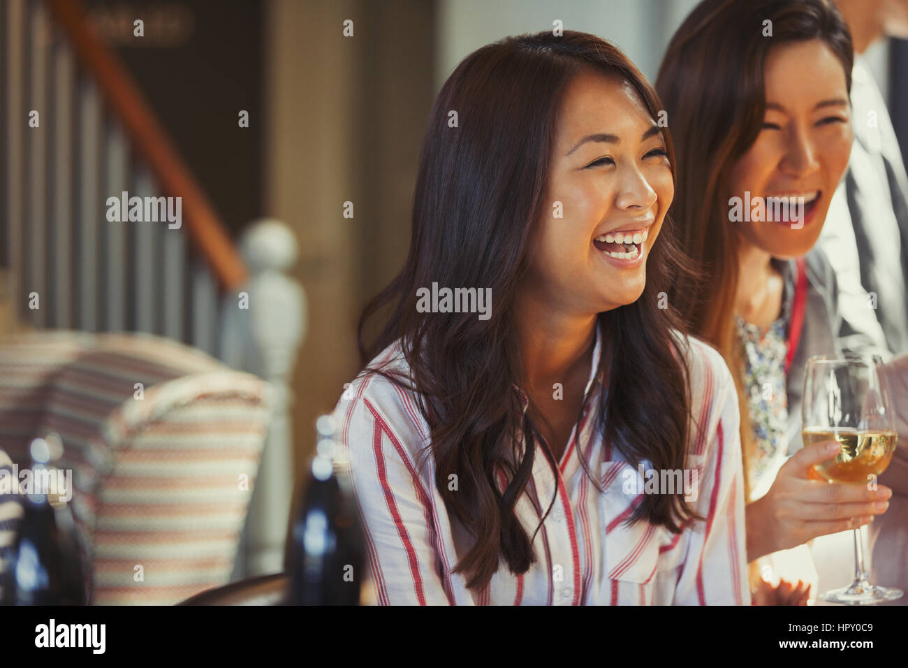 Laughing women friends drinking wine at bar Stock Photo