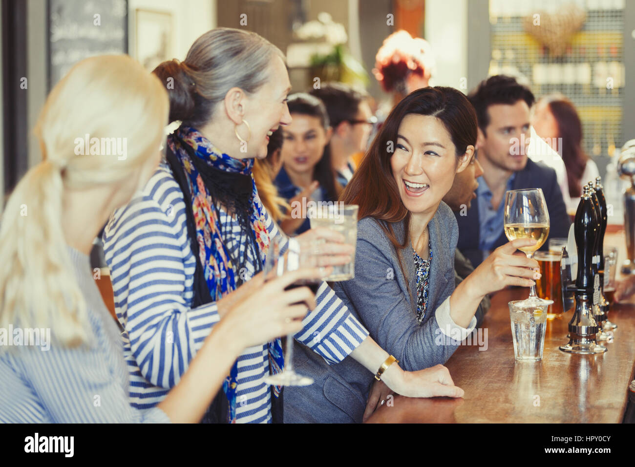 Smiling women friends drinking wine at bar Stock Photo