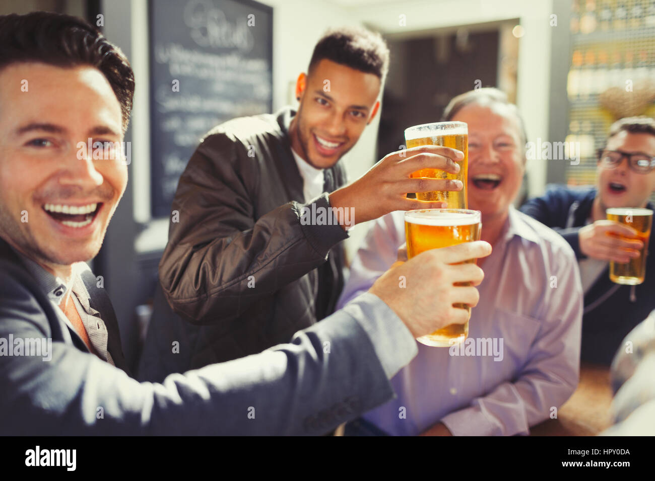 Enthusiastic men friends toasting beer glasses at bar Stock Photo