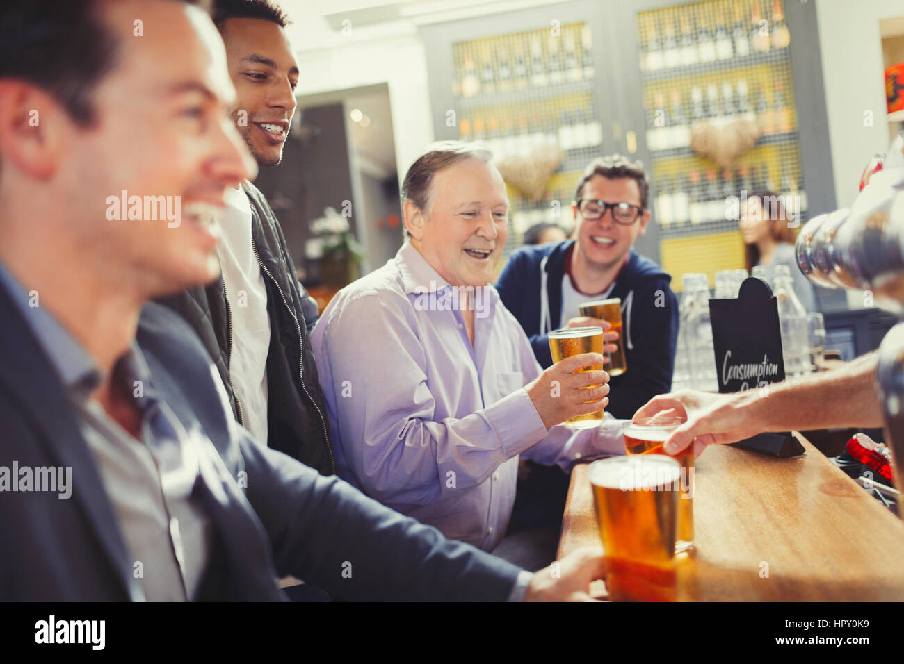 Smiling men friends drinking beer at bar Stock Photo