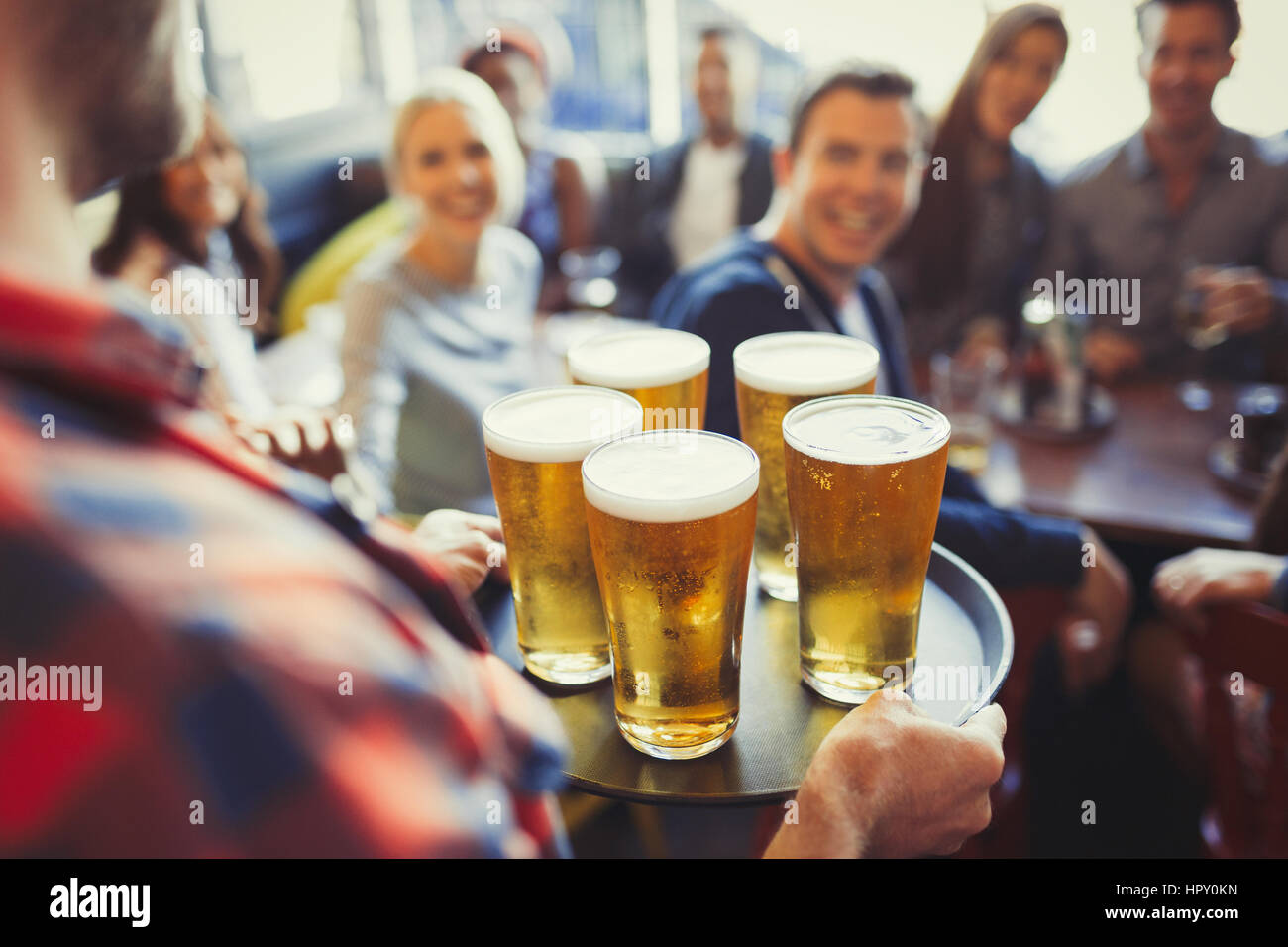 Bartender serving tray of beers to friends in bar Stock Photo
