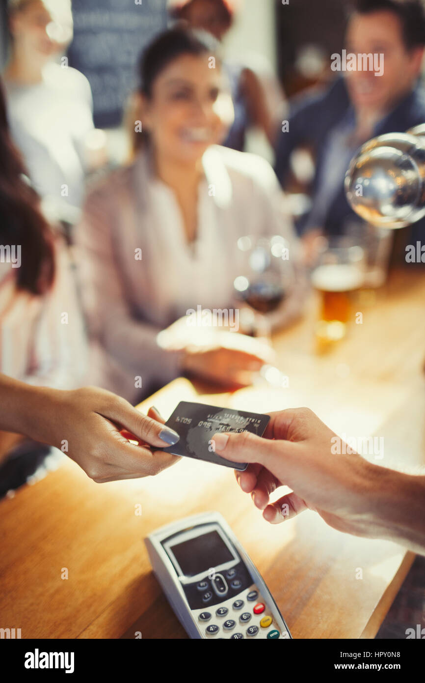 Woman paying bartender with credit card at bar Stock Photo
