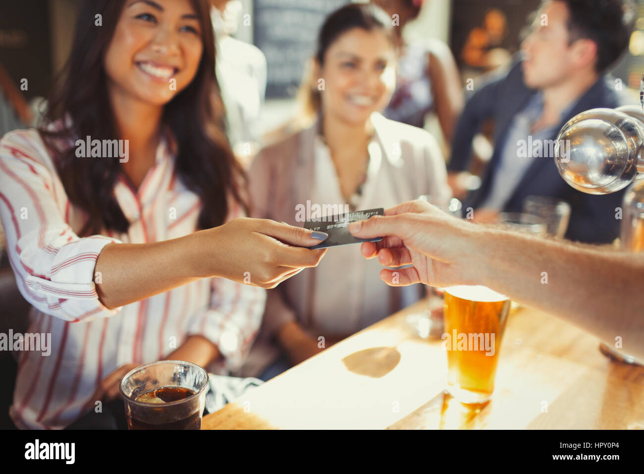 Smiling woman paying bartender with credit card at bar Stock Photo