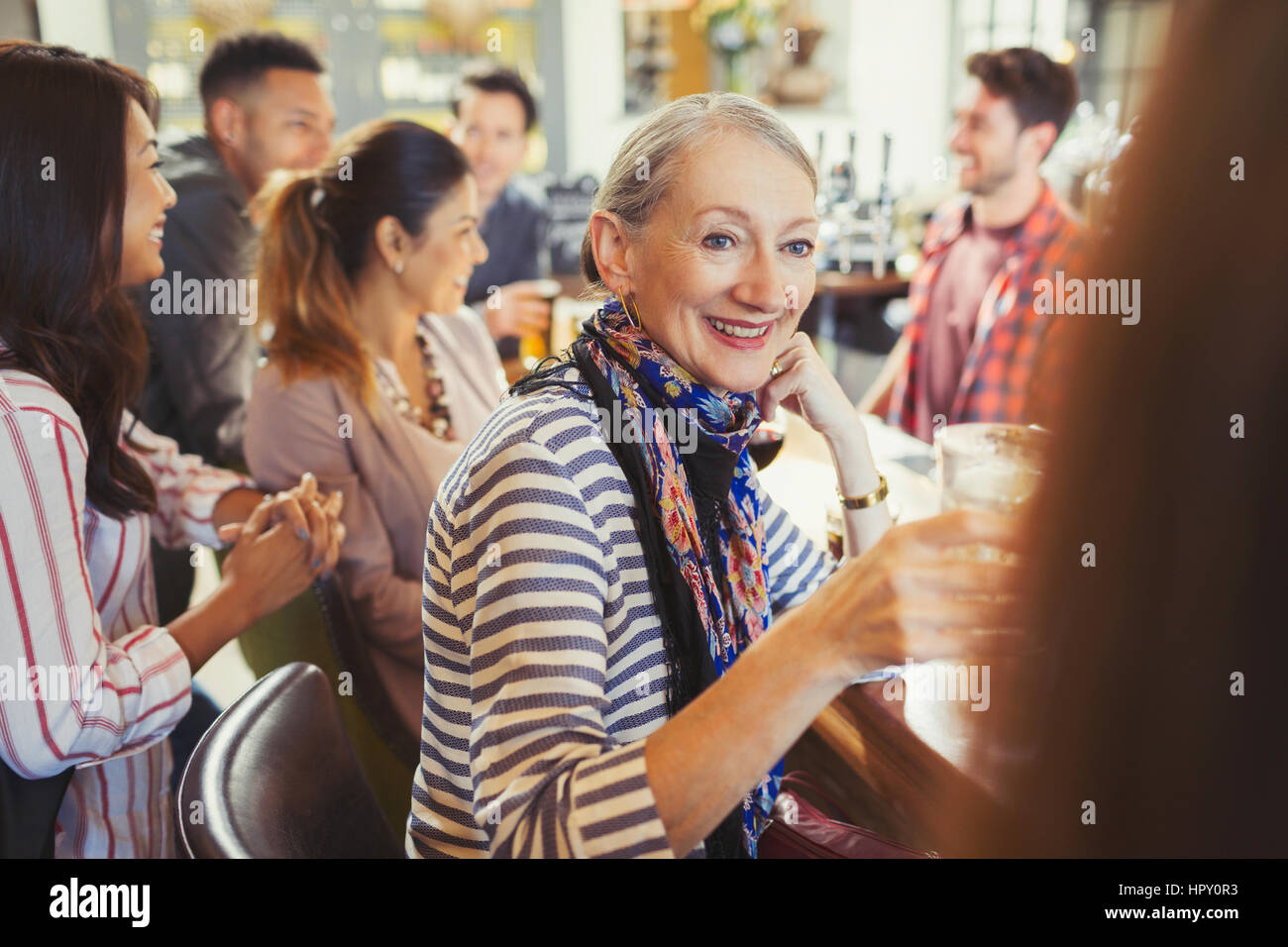 Smiling senior woman drinking and talking with friend at bar Stock Photo