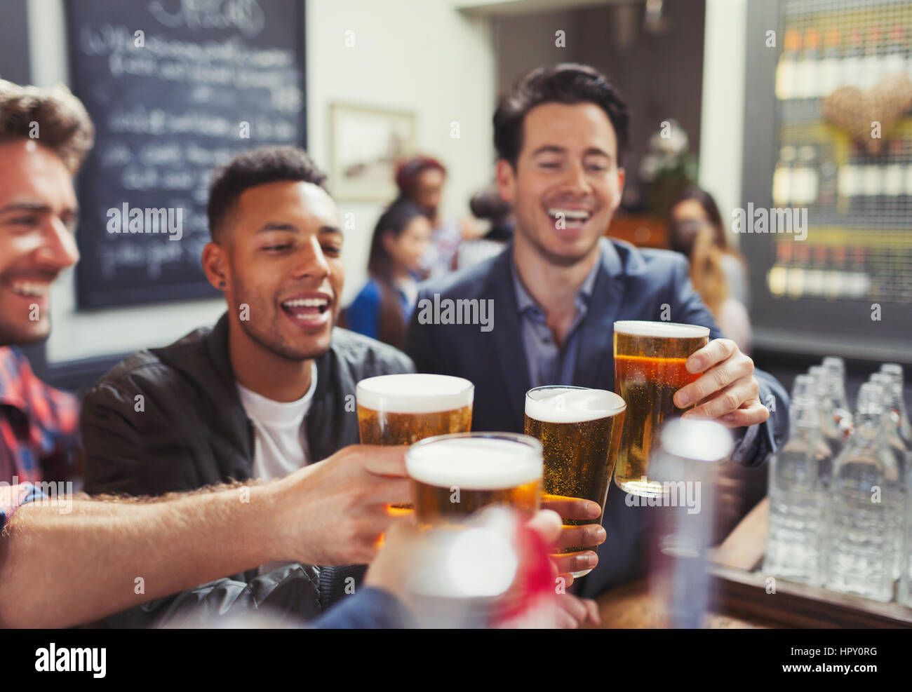 Men friends toasting beer glasses at bar Stock Photo