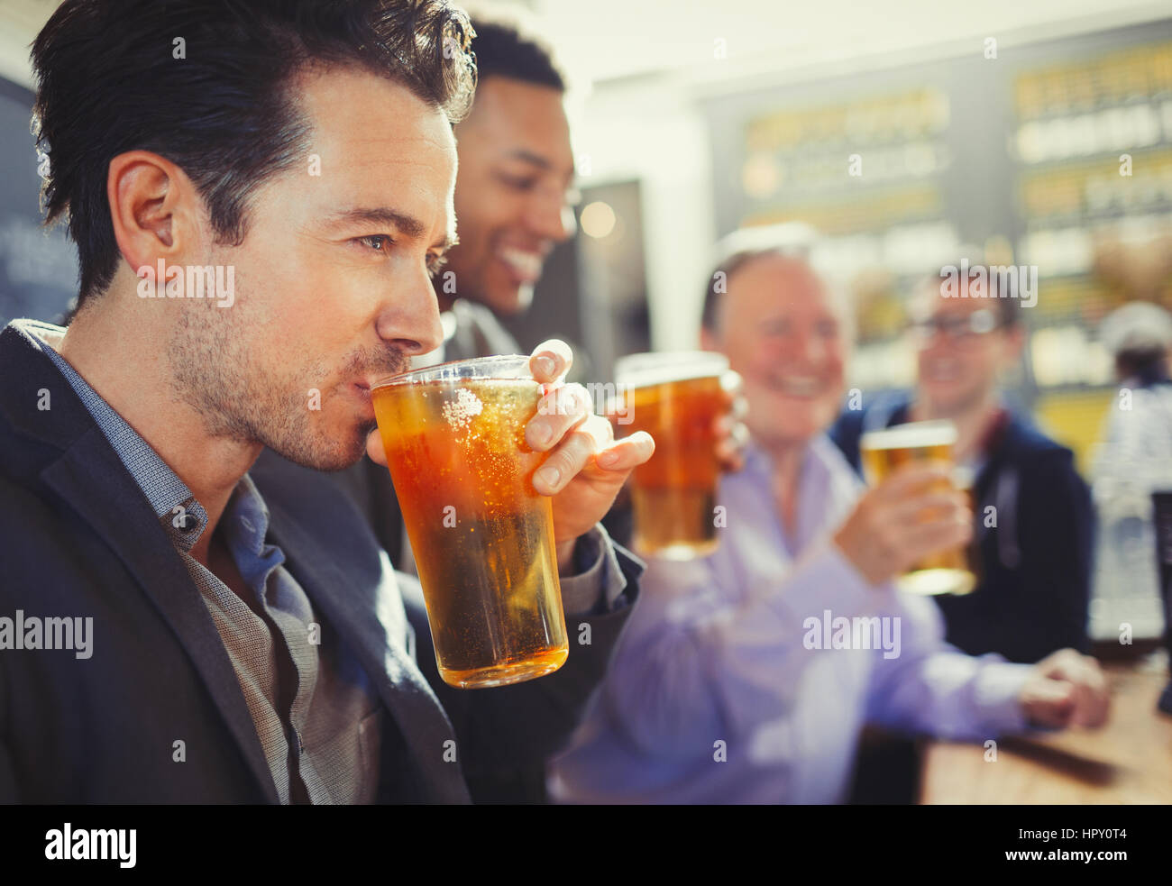 Man drinking beer with friends at bar Stock Photo