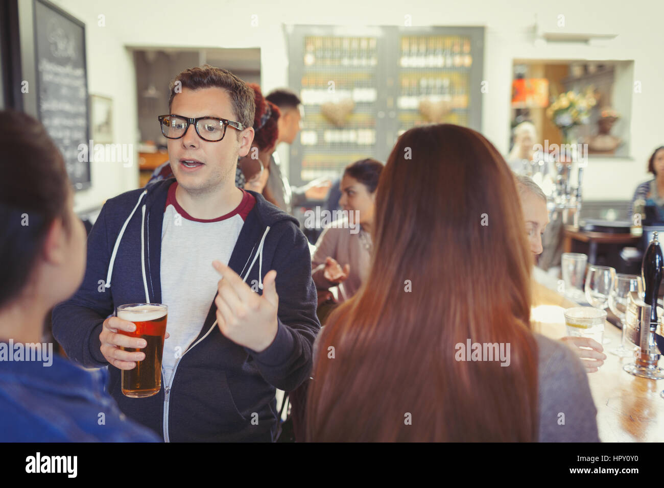Man drinking beer and talking to woman at bar Stock Photo