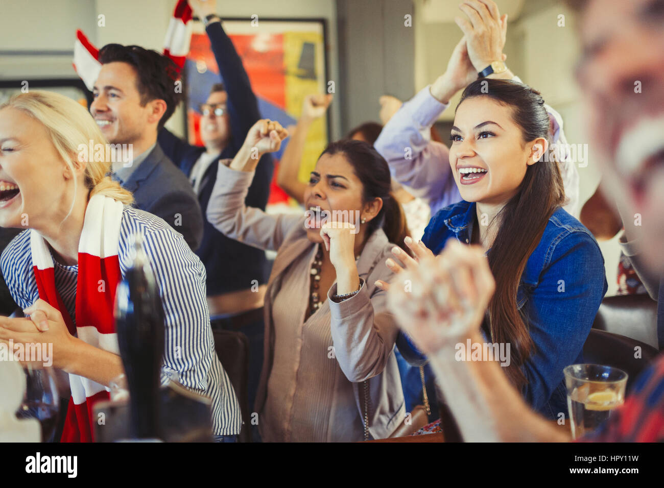 Enthusiastic sports fans cheering watching game at bar Stock Photo