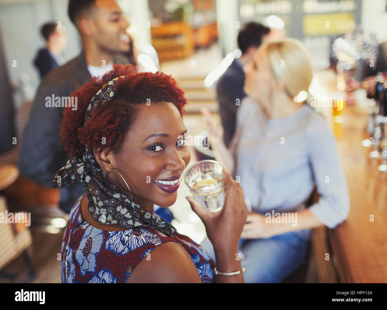 Portrait smiling woman drinking water and talking with friends at bar Stock Photo