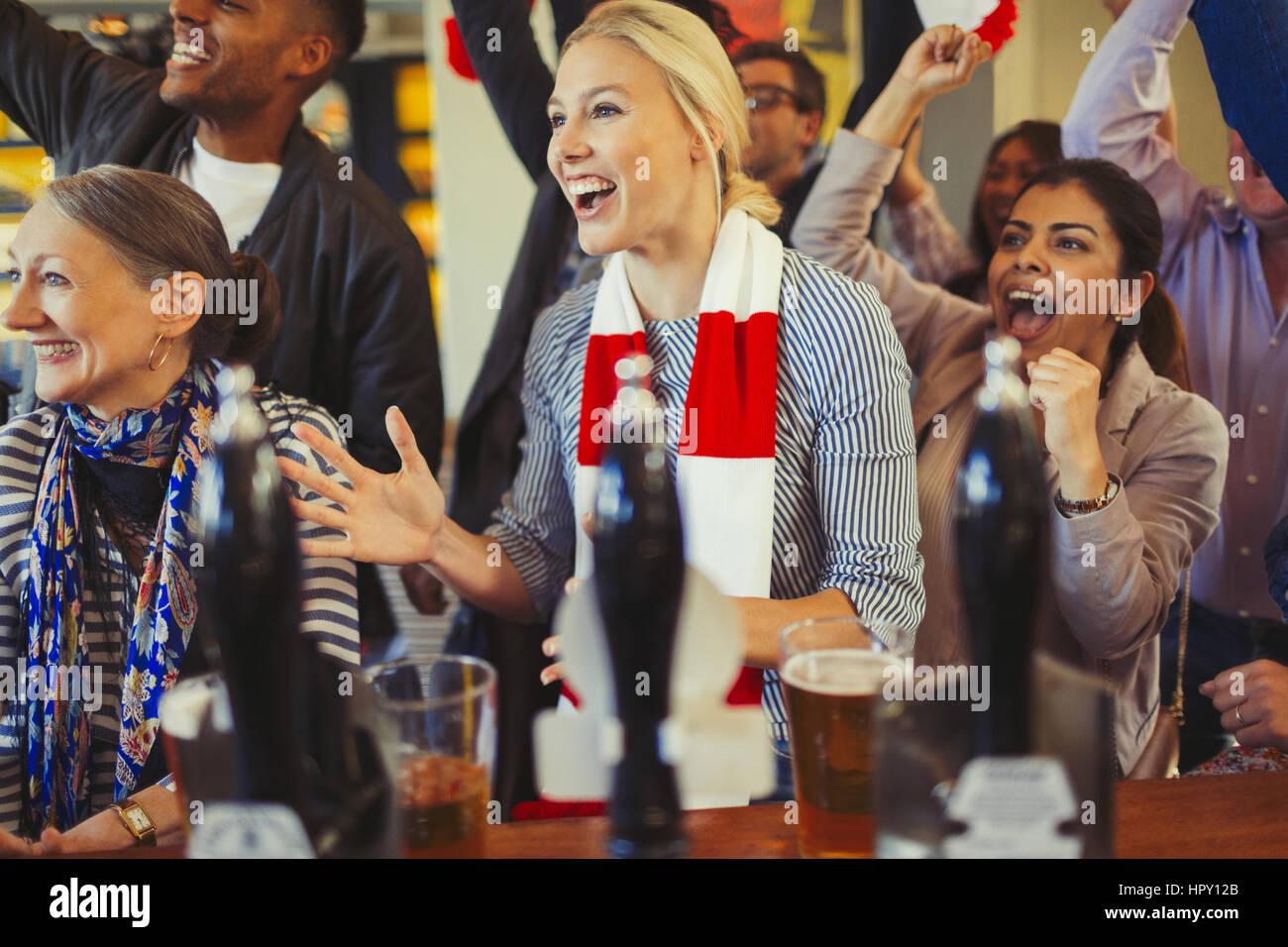 Enthusiastic sports fans cheering and watching game at bar Stock Photo
