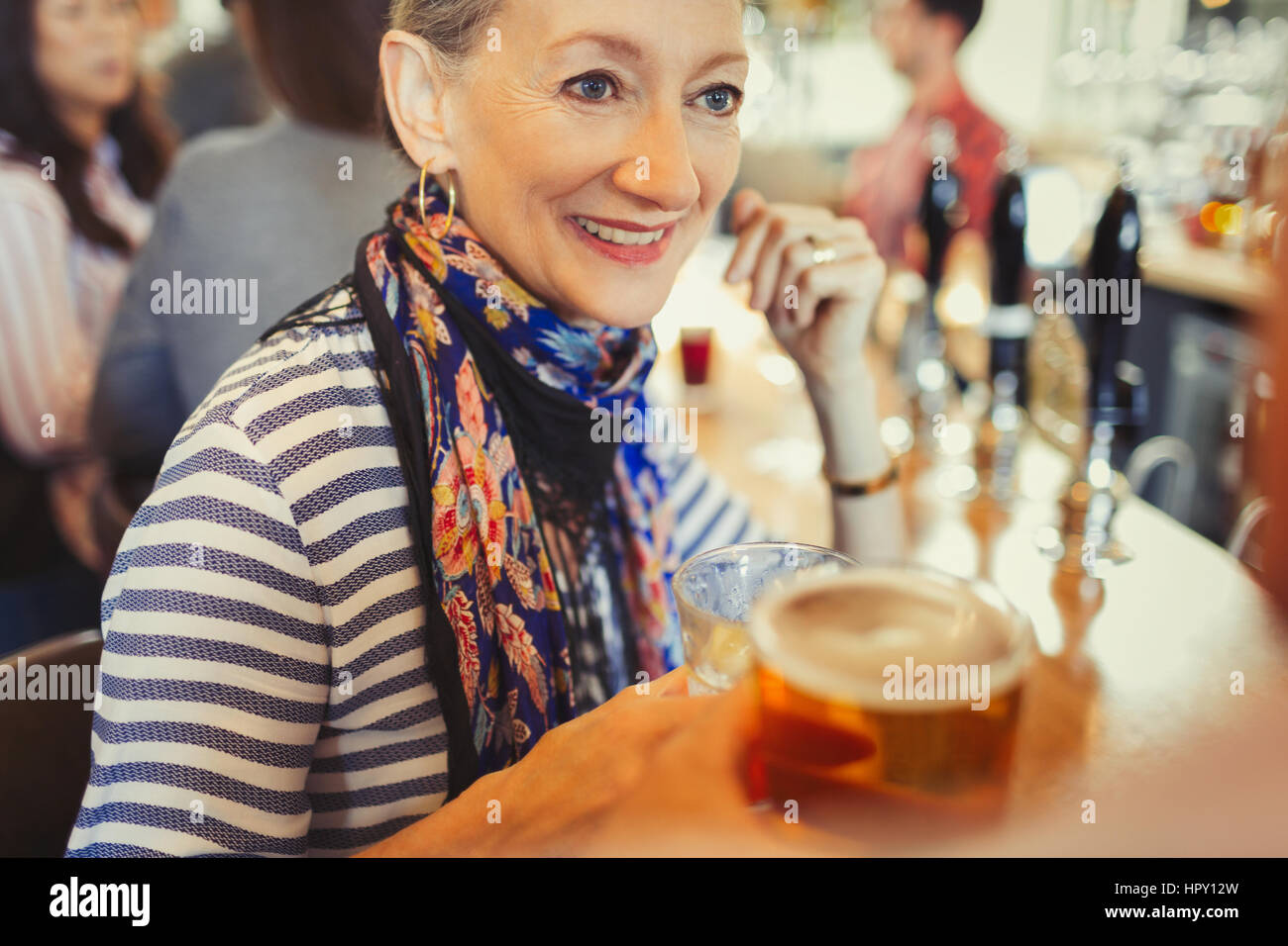 Senior woman drinking beer at bar Stock Photo