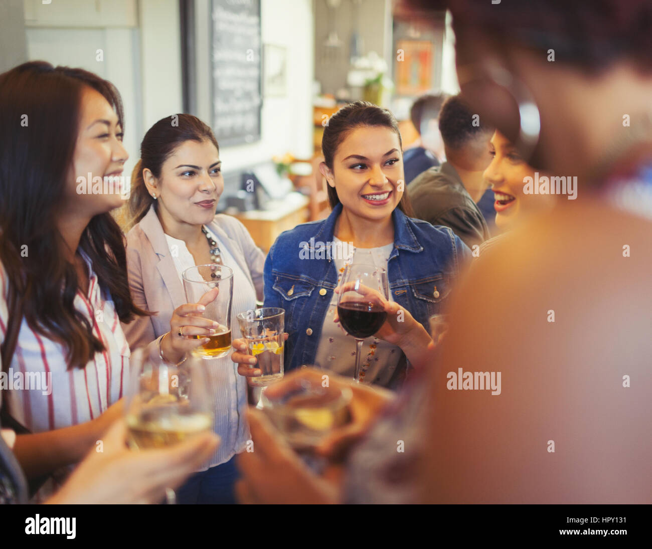 Women friends talking and drinking beer and wine at bar Stock Photo