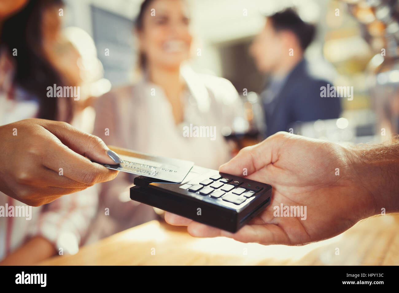Woman with credit card paying bartender with contactless payment at bar Stock Photo