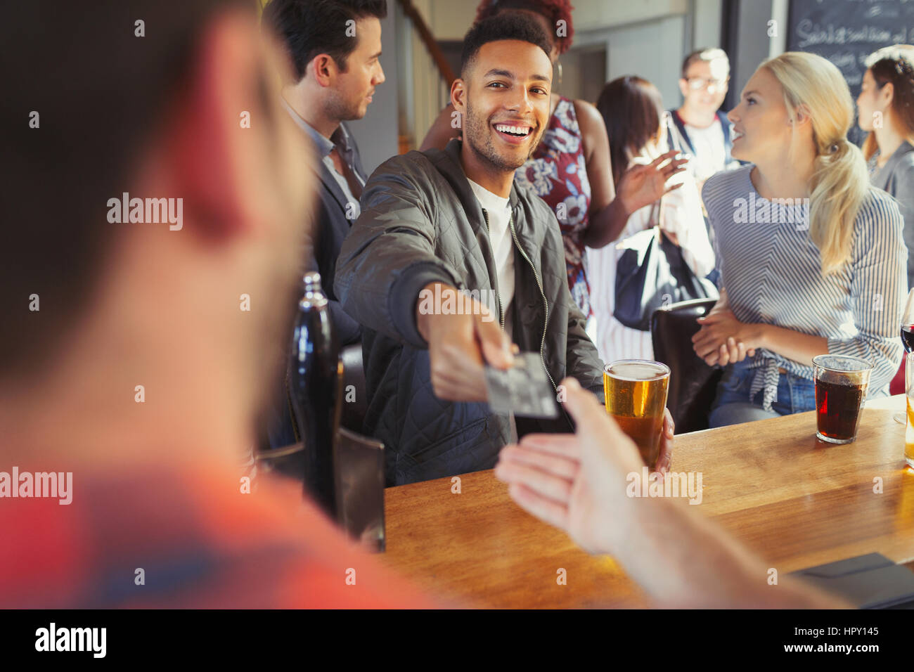 Smiling man paying bartender with credit card at bar Stock Photo