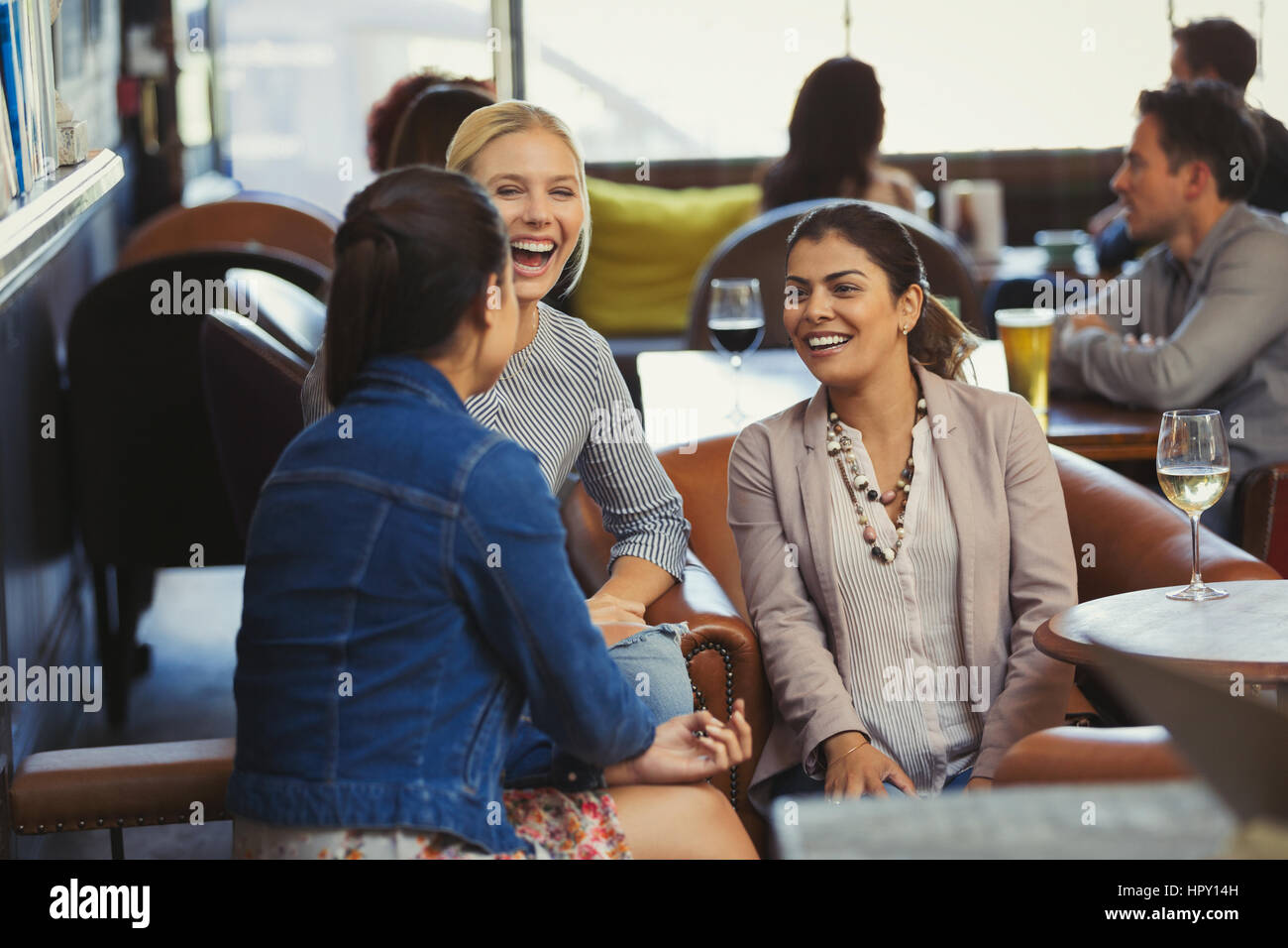 Laughing women friends talking and drinking wine in bar Stock Photo